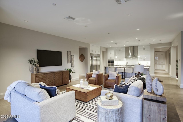 living area featuring light wood-type flooring, visible vents, baseboards, and recessed lighting