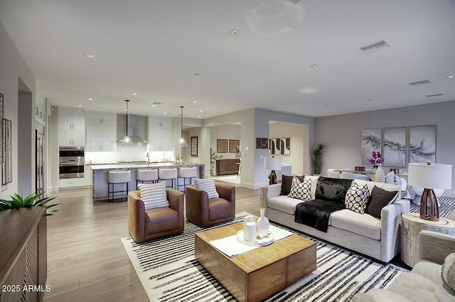 living room featuring light wood-style floors, visible vents, and recessed lighting