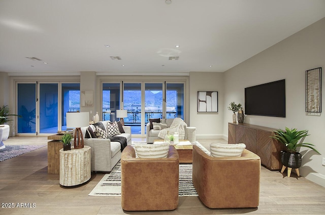 living area with light wood-style floors, recessed lighting, visible vents, and baseboards