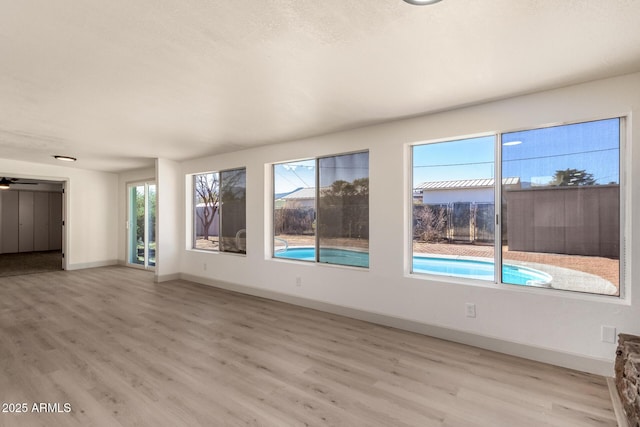 spare room with light wood-type flooring, ceiling fan, and a wealth of natural light