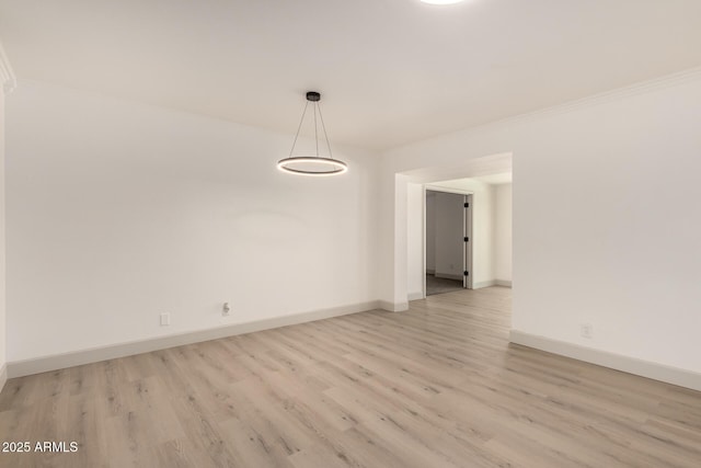 spare room featuring crown molding and light hardwood / wood-style flooring