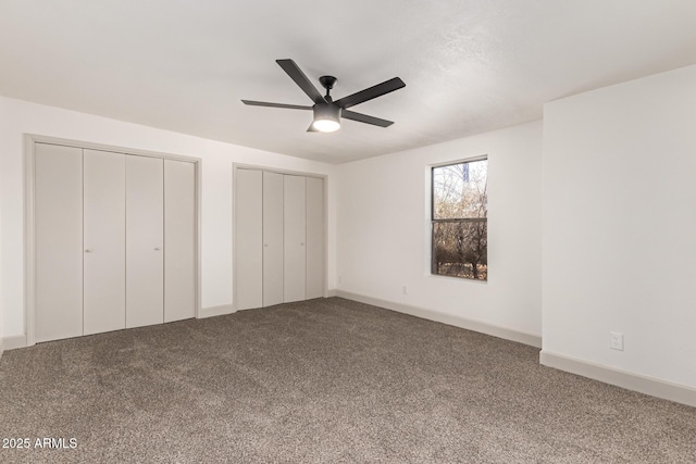 unfurnished bedroom featuring ceiling fan, multiple closets, and carpet