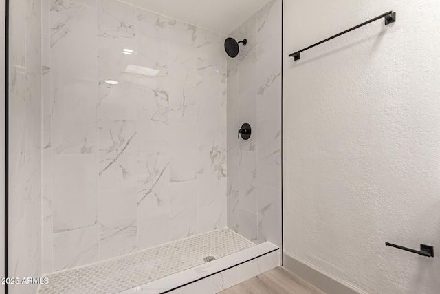 bathroom featuring wood-type flooring and tiled shower