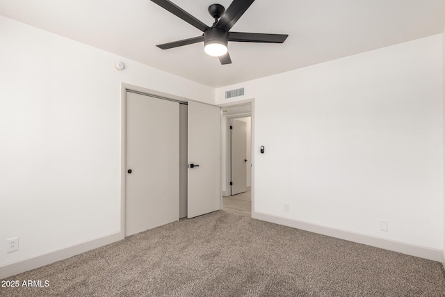 unfurnished bedroom featuring ceiling fan, a closet, and light carpet