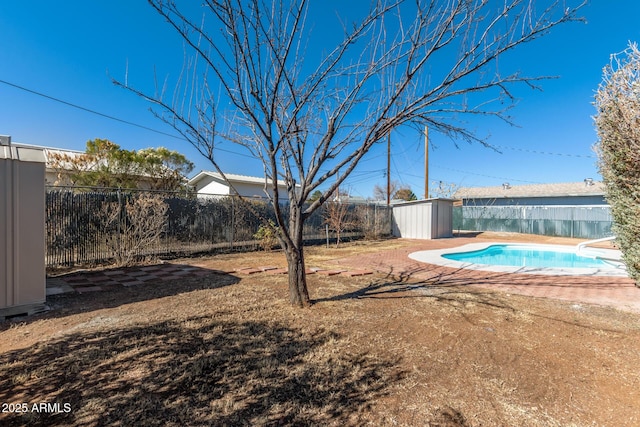 view of yard with a fenced in pool and a storage shed