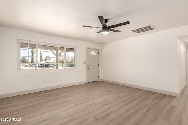 foyer with ceiling fan, brick wall, and light hardwood / wood-style flooring