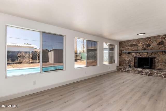 unfurnished living room with a stone fireplace and light hardwood / wood-style flooring