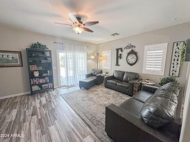 living room featuring ceiling fan, wood-type flooring, and a textured ceiling