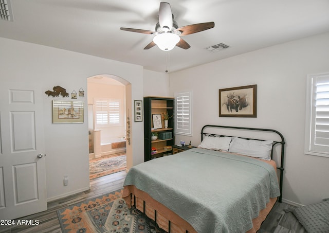 bedroom featuring multiple windows, wood-type flooring, ceiling fan, and ensuite bathroom