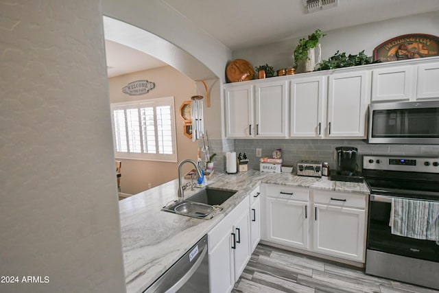 kitchen with sink, white cabinetry, light stone counters, appliances with stainless steel finishes, and decorative backsplash