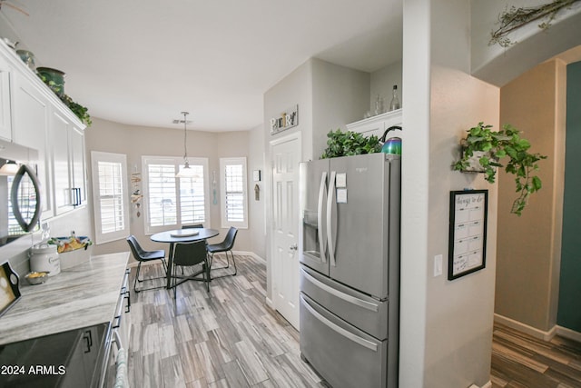 kitchen featuring pendant lighting, white cabinets, stainless steel fridge, light stone counters, and light hardwood / wood-style floors