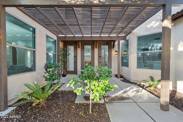 view of exterior entry featuring a pergola, french doors, and a patio