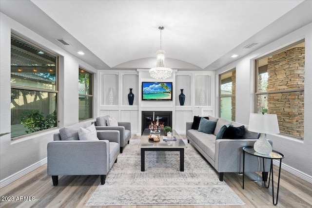 living room featuring a chandelier, vaulted ceiling, and light hardwood / wood-style floors