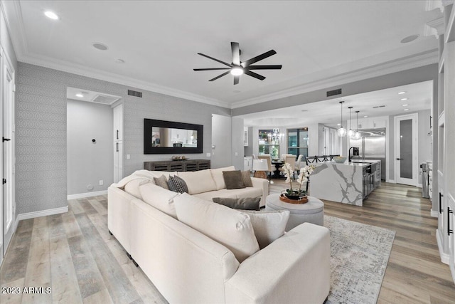 living room featuring french doors, ceiling fan with notable chandelier, ornamental molding, light wood-type flooring, and sink