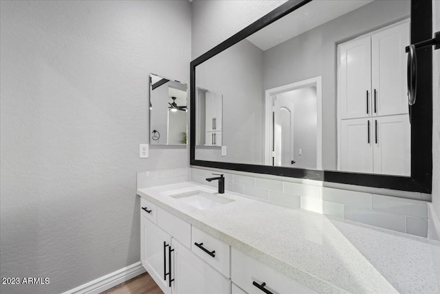 bathroom with ceiling fan, oversized vanity, tasteful backsplash, and hardwood / wood-style floors