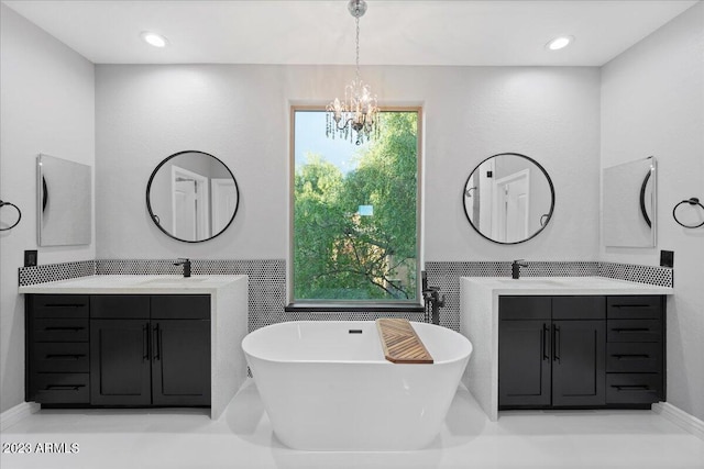 bathroom with double sink vanity, a bathing tub, and a notable chandelier