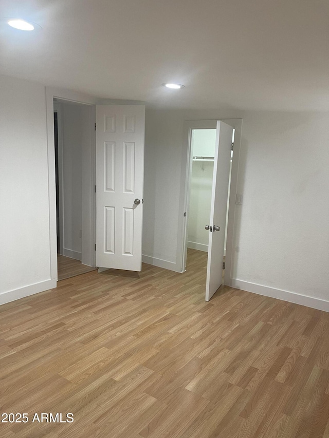 unfurnished bedroom featuring a closet, a spacious closet, and light hardwood / wood-style flooring