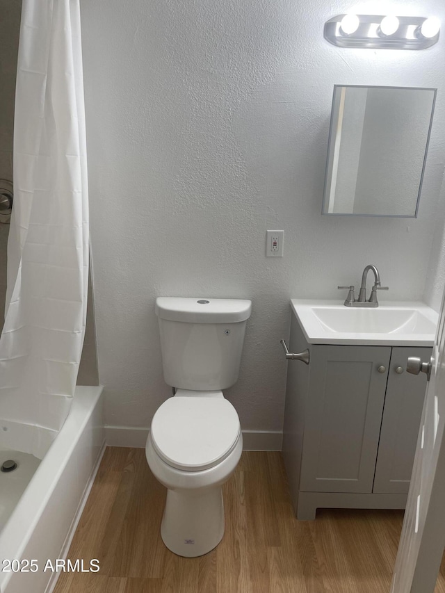 full bathroom featuring hardwood / wood-style floors, vanity, shower / tub combo, and toilet