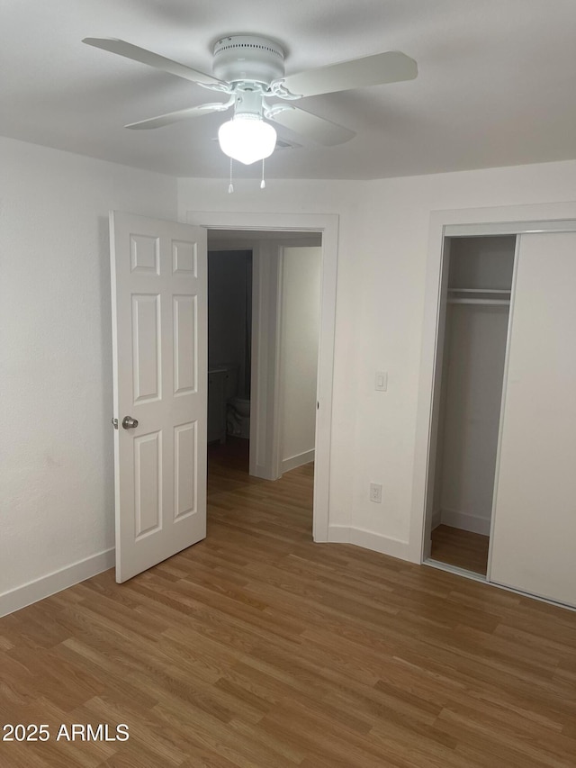 unfurnished bedroom featuring ceiling fan, a closet, and wood-type flooring