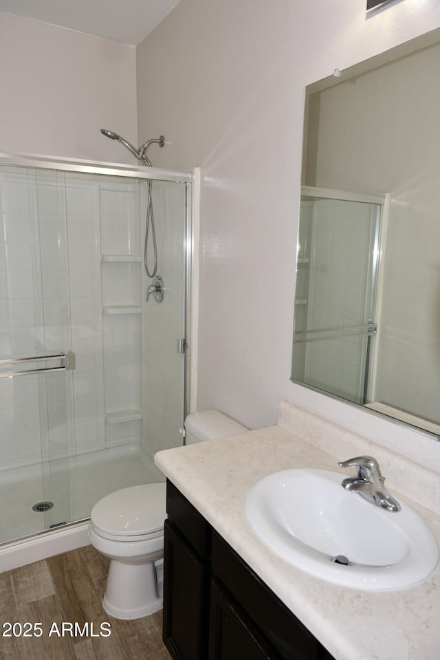 bathroom featuring vanity, wood finished floors, toilet, and a shower stall