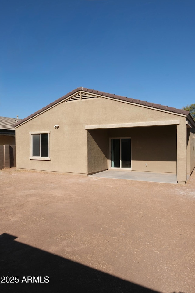 rear view of house featuring a patio area and stucco siding