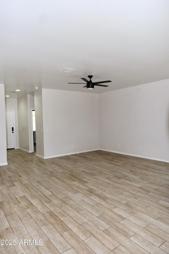 spare room featuring a ceiling fan, visible vents, light wood-style flooring, and baseboards