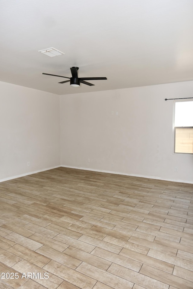 spare room featuring light wood-style floors, ceiling fan, visible vents, and baseboards