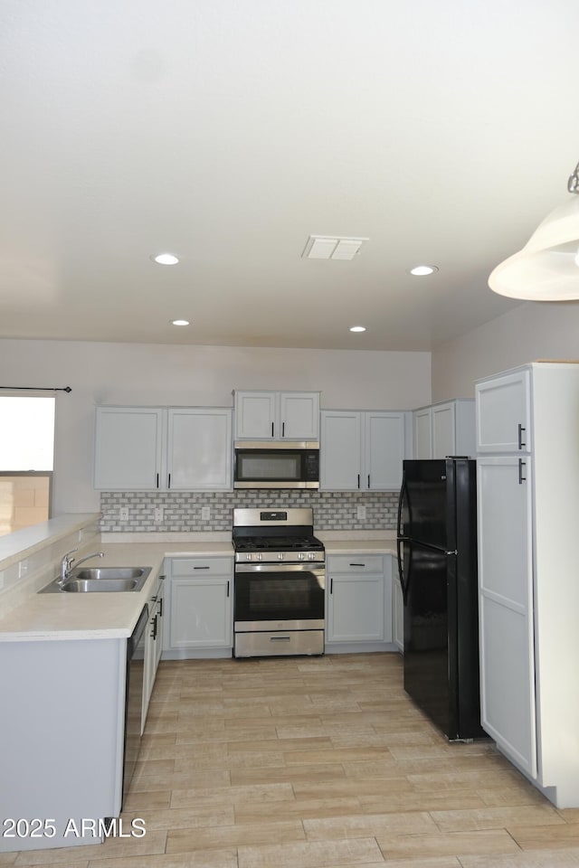 kitchen with decorative backsplash, light countertops, black appliances, white cabinetry, and a sink