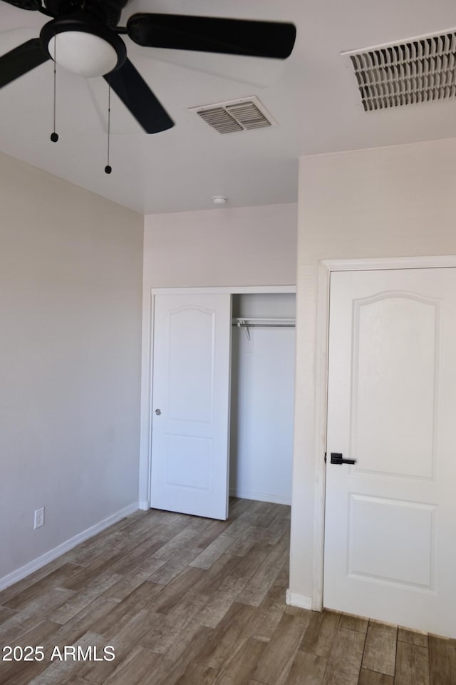 unfurnished bedroom featuring light wood-style flooring, a closet, visible vents, and baseboards