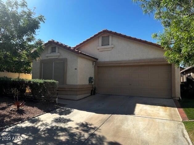 view of front of home featuring a garage, stucco siding, a tiled roof, and concrete driveway