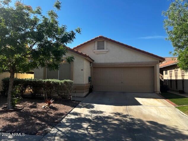 view of front of house with a tile roof, an attached garage, driveway, and stucco siding