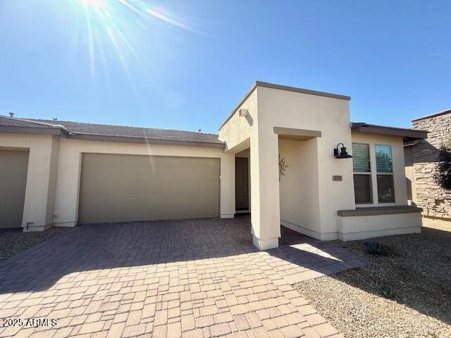 view of front of home featuring decorative driveway, an attached garage, and stucco siding