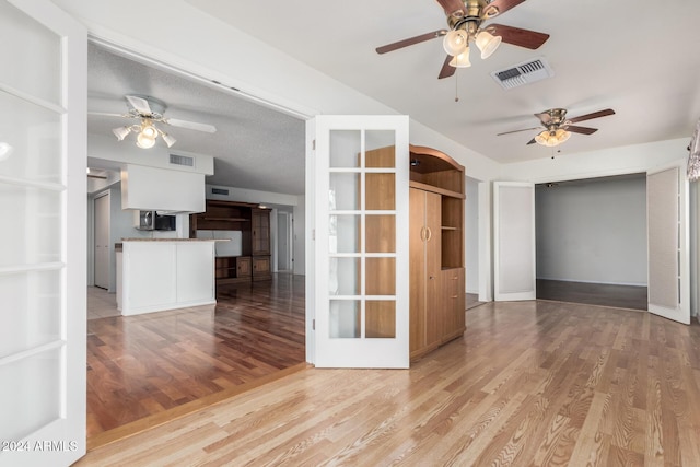 unfurnished room with french doors, a textured ceiling, light hardwood / wood-style floors, and ceiling fan