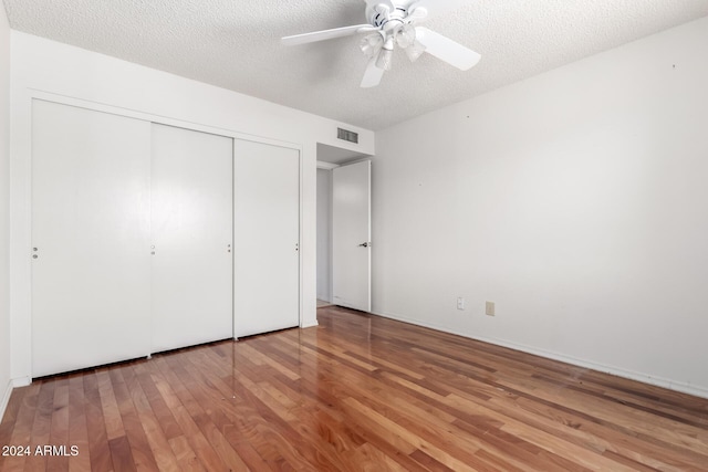 unfurnished bedroom with a closet, ceiling fan, hardwood / wood-style floors, and a textured ceiling