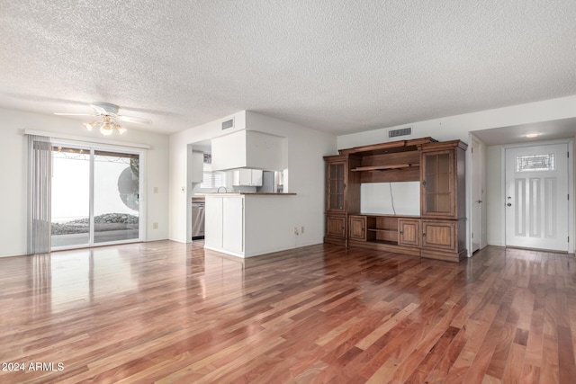 unfurnished living room with ceiling fan, sink, light hardwood / wood-style floors, and a textured ceiling