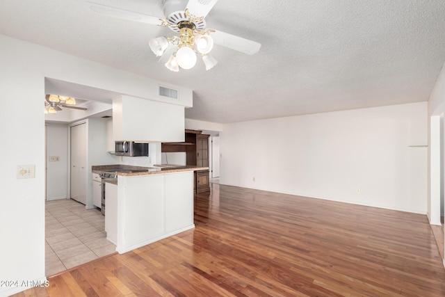 kitchen featuring white cabinetry, ceiling fan, kitchen peninsula, light hardwood / wood-style floors, and a textured ceiling