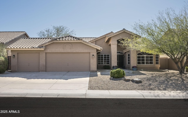 view of front of property with stucco siding, driveway, a tile roof, fence, and a garage