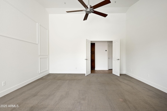 carpeted empty room featuring high vaulted ceiling, baseboards, and ceiling fan