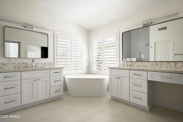 bathroom featuring visible vents, a freestanding tub, a sink, and vaulted ceiling