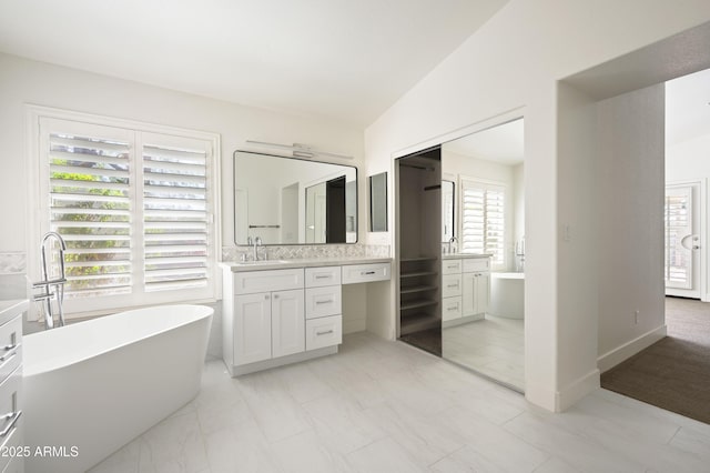 bathroom featuring lofted ceiling, a soaking tub, and vanity