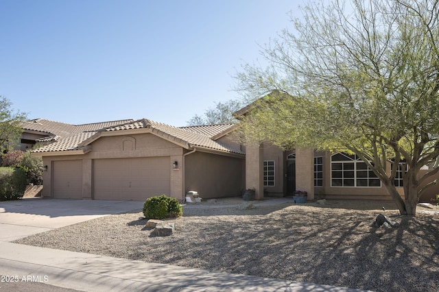 view of front of home featuring a tiled roof, stucco siding, an attached garage, and driveway