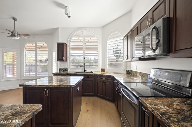 kitchen with a ceiling fan, a sink, dark brown cabinetry, light wood-style floors, and appliances with stainless steel finishes