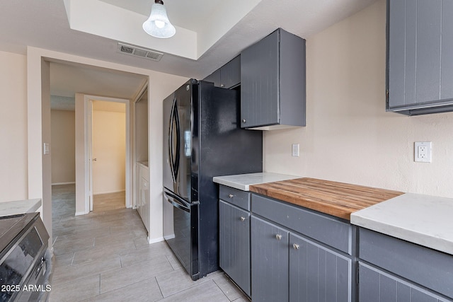 kitchen with visible vents, light countertops, gray cabinets, freestanding refrigerator, and range