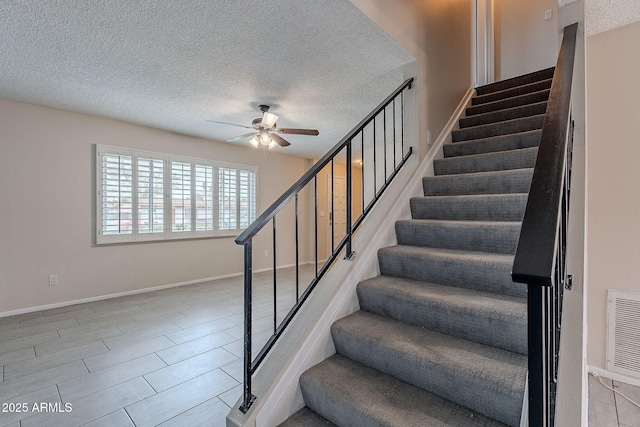 stairs with visible vents, baseboards, a textured ceiling, and ceiling fan