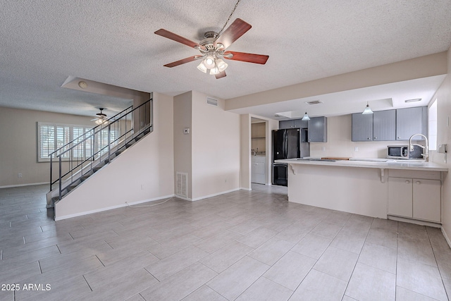 kitchen featuring visible vents, open floor plan, a peninsula, light countertops, and ceiling fan