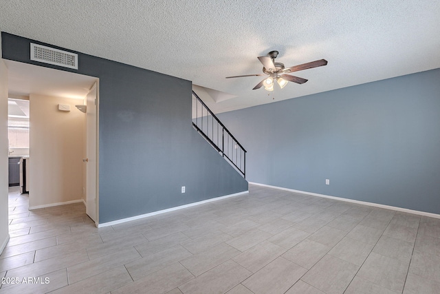 spare room featuring visible vents, baseboards, ceiling fan, stairs, and a textured ceiling