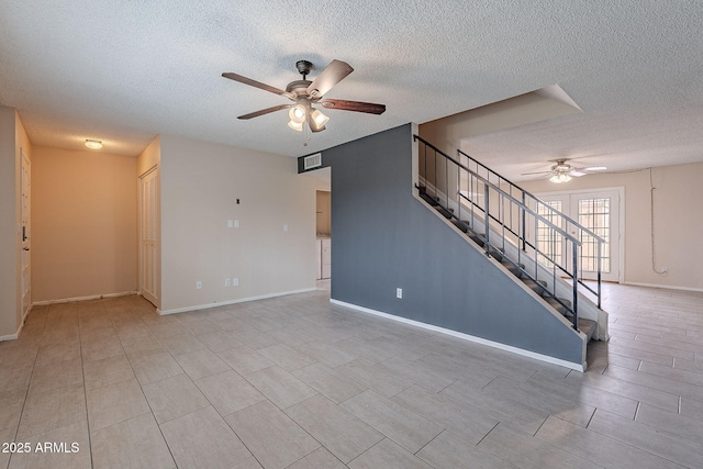 unfurnished living room with baseboards, a textured ceiling, ceiling fan, and stairs