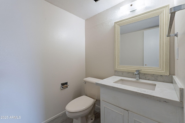 half bathroom featuring vanity, toilet, and baseboards