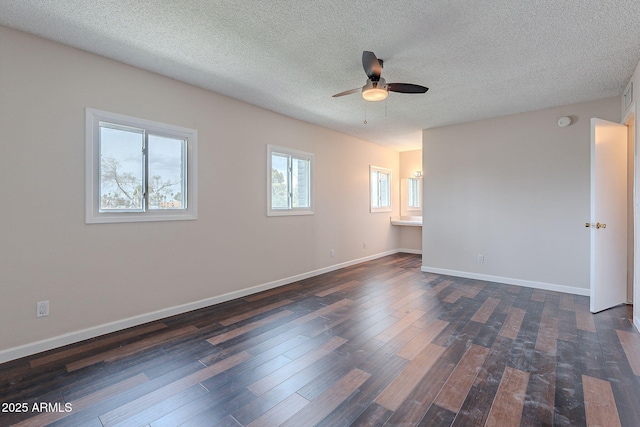 empty room with dark wood-style floors, a textured ceiling, baseboards, and a ceiling fan