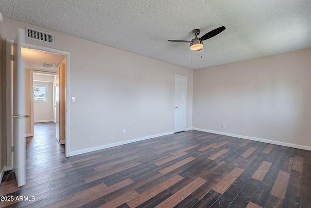 spare room with visible vents, baseboards, dark wood-type flooring, and a ceiling fan